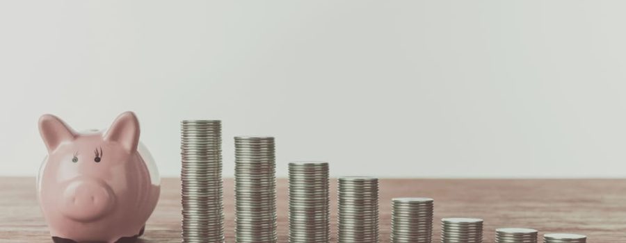 piggy bank next to stacks of coins