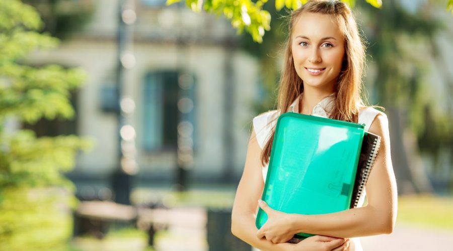 Student woman is standing with the folder and copy-book on the u
